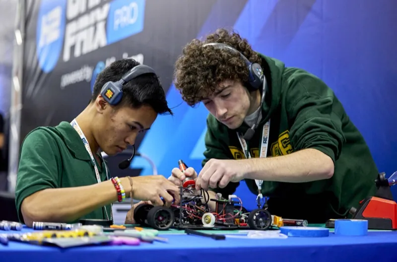 Dos estudiantes ensamblando y calibrando la electrónica de un auto H2GP Pro en una competencia internacional del H2 Grand Prix
