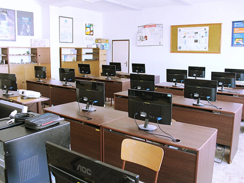 Sala de informática con filas de computadores de escritorio y monitores