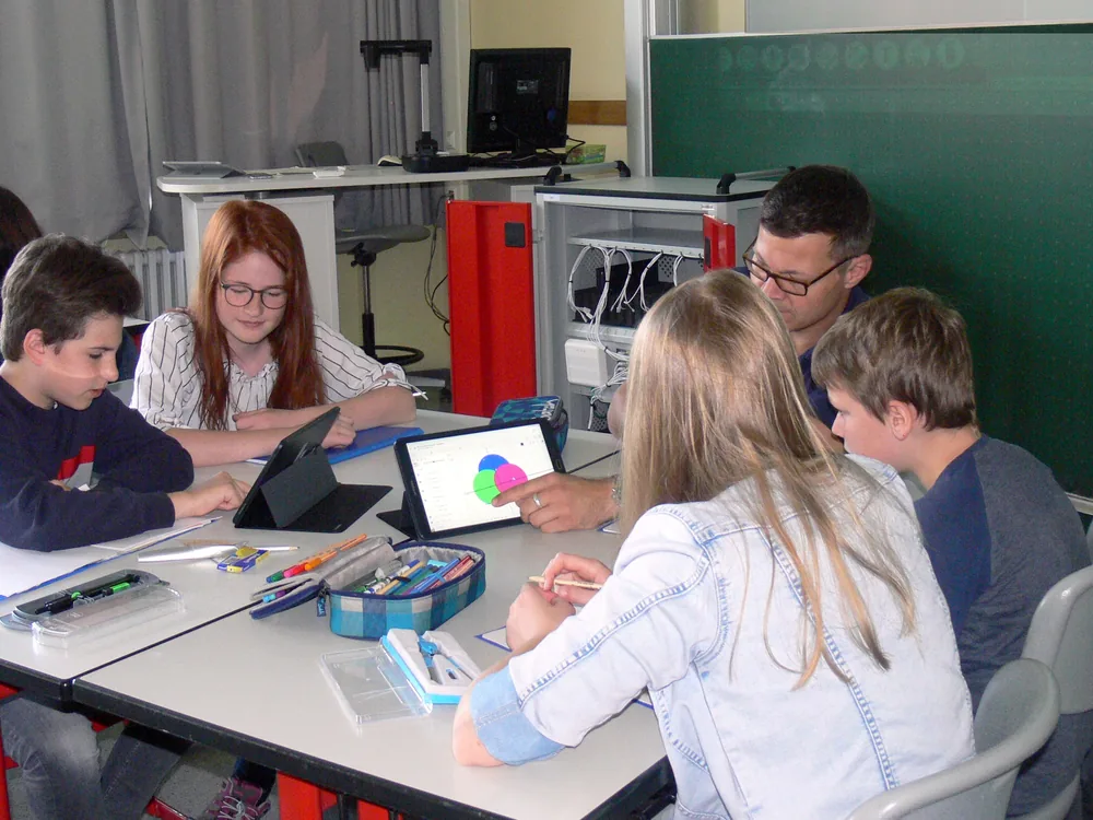 Estudiantes y docente trabajando con tablets en el aula